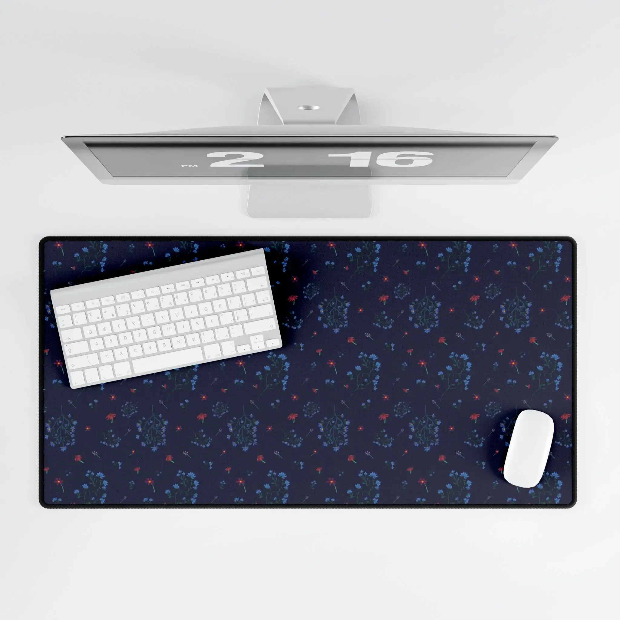 A large desk mat featuring the Woodland Bloom floral pattern in deep blue, with soft florals in warm autumn shades. Shown flat on a tidy desk with accessories.