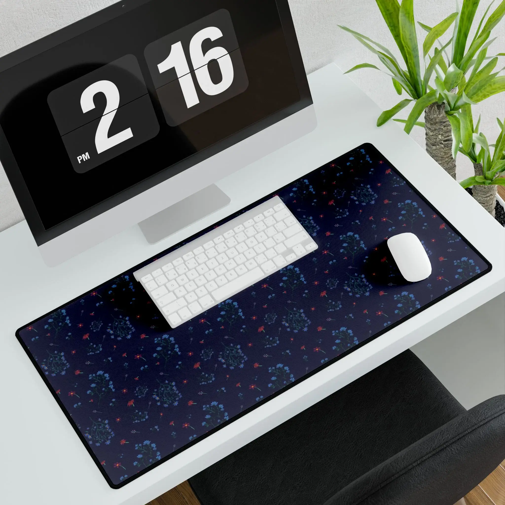 A large desk mat featuring the Woodland Bloom floral pattern in deep blue, with soft florals in warm autumn shades. Shown flat on a tidy desk with accessories.
