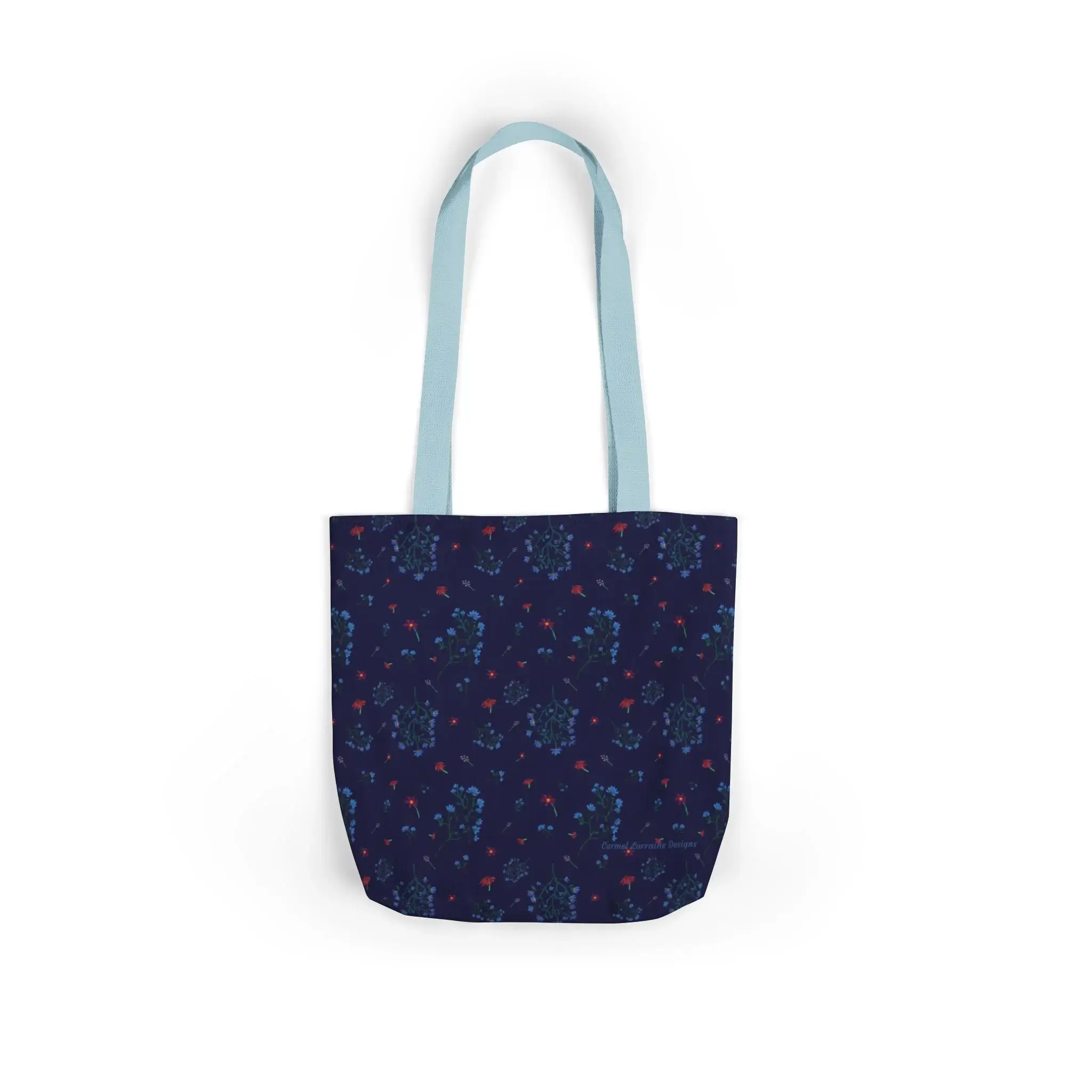 Canvas tote bag featuring the Woodland Bloom floral pattern with light blue straps, styled against a soft background.