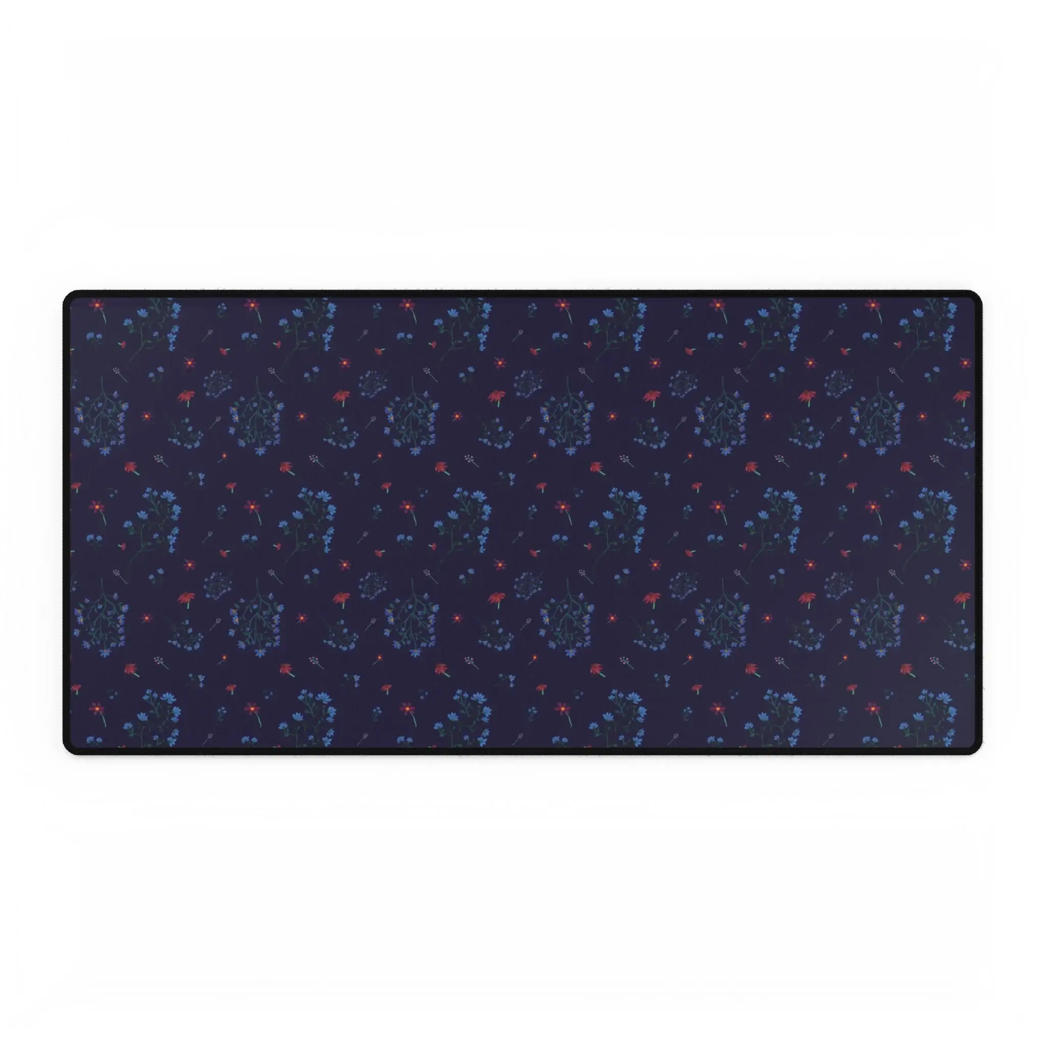 A large desk mat featuring the Woodland Bloom floral pattern in deep blue, with soft florals in warm autumn shades. Shown flat on a tidy desk with accessories.