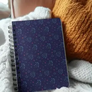 Spiral notebook with a deep blue floral cover design from the Woodland Bloom collection, featuring soft wildflower tones and metal binding.
